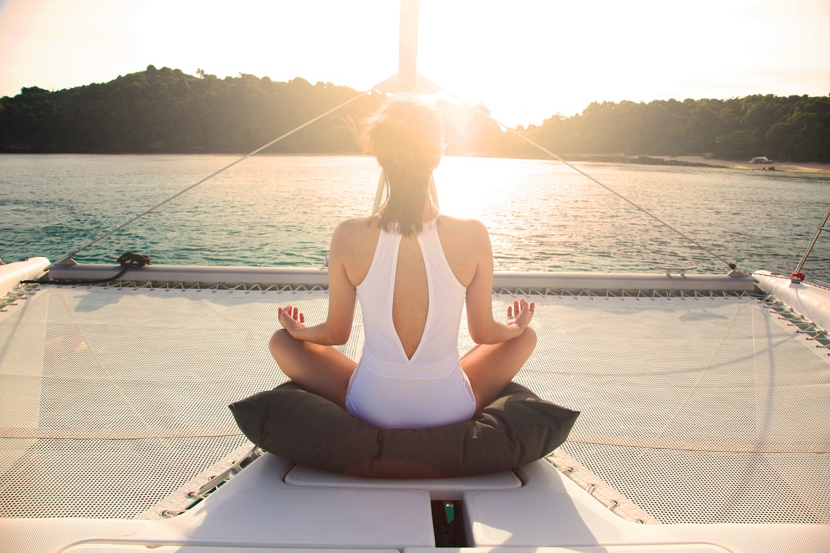A woman is doing yoga. Yoga is an exceptional sport to do on a yacht due to its many benefits.
