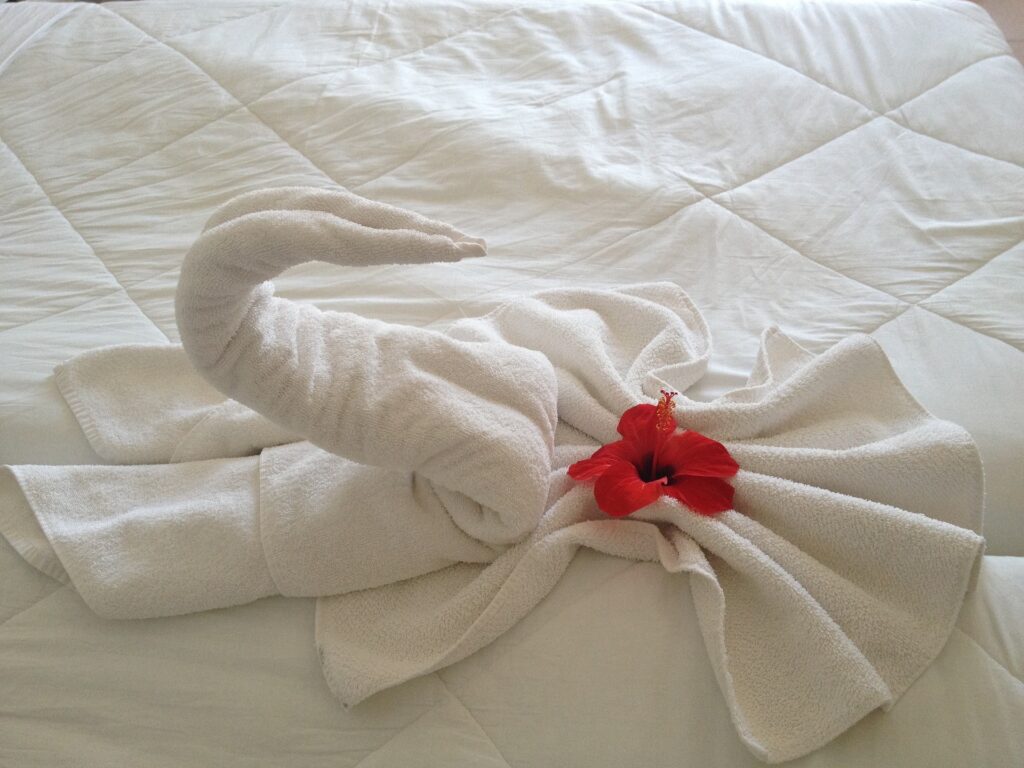 A swan-shaped towel on a bed.